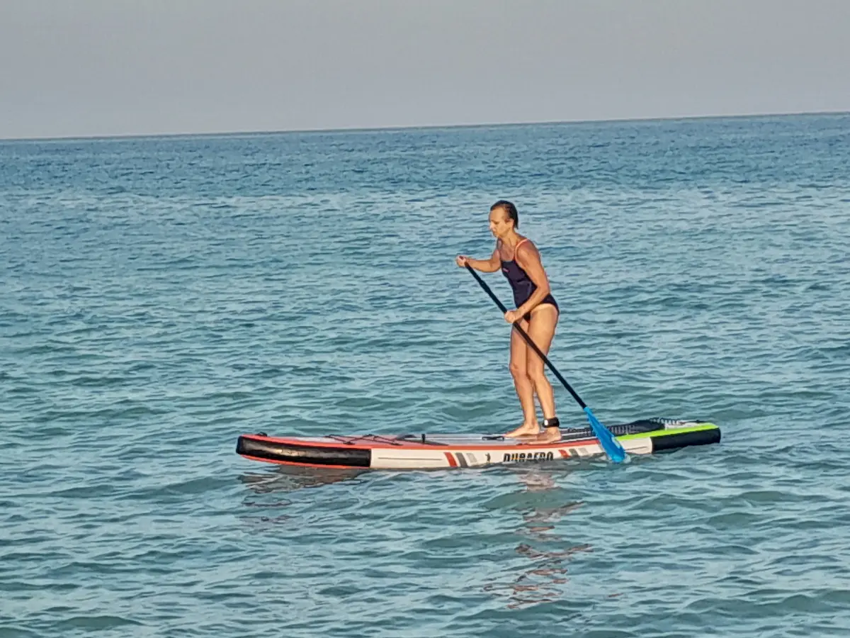 Rakel haciendo paddle surf sola en mar abierto al atardecer