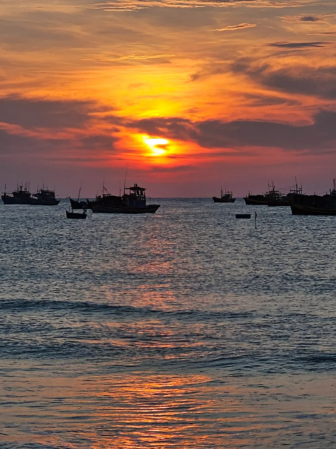 Amanecer sobre el agua en Vietnam con barcas de pesca recortadas al fondo
