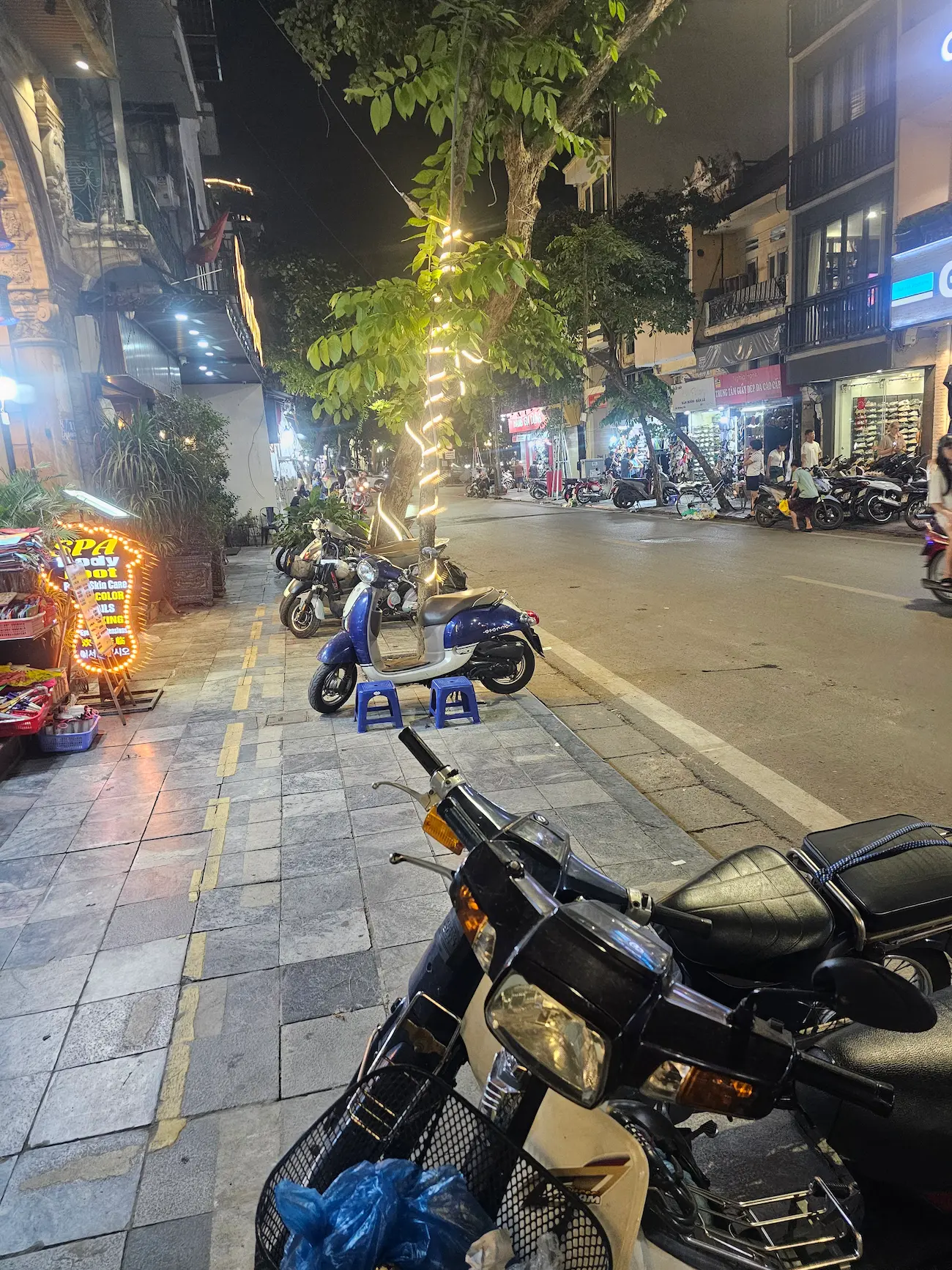 Calle de Hanói con rótulos, cables y motos al atardecer, Vietnam