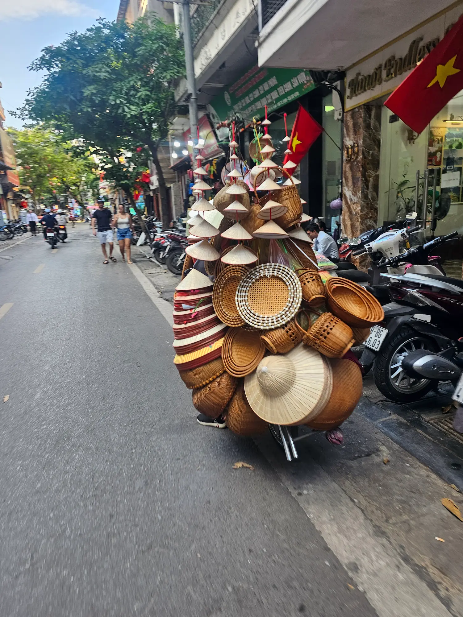 Moto transportando una carga enorme de sombreros por una calle de Vietnam