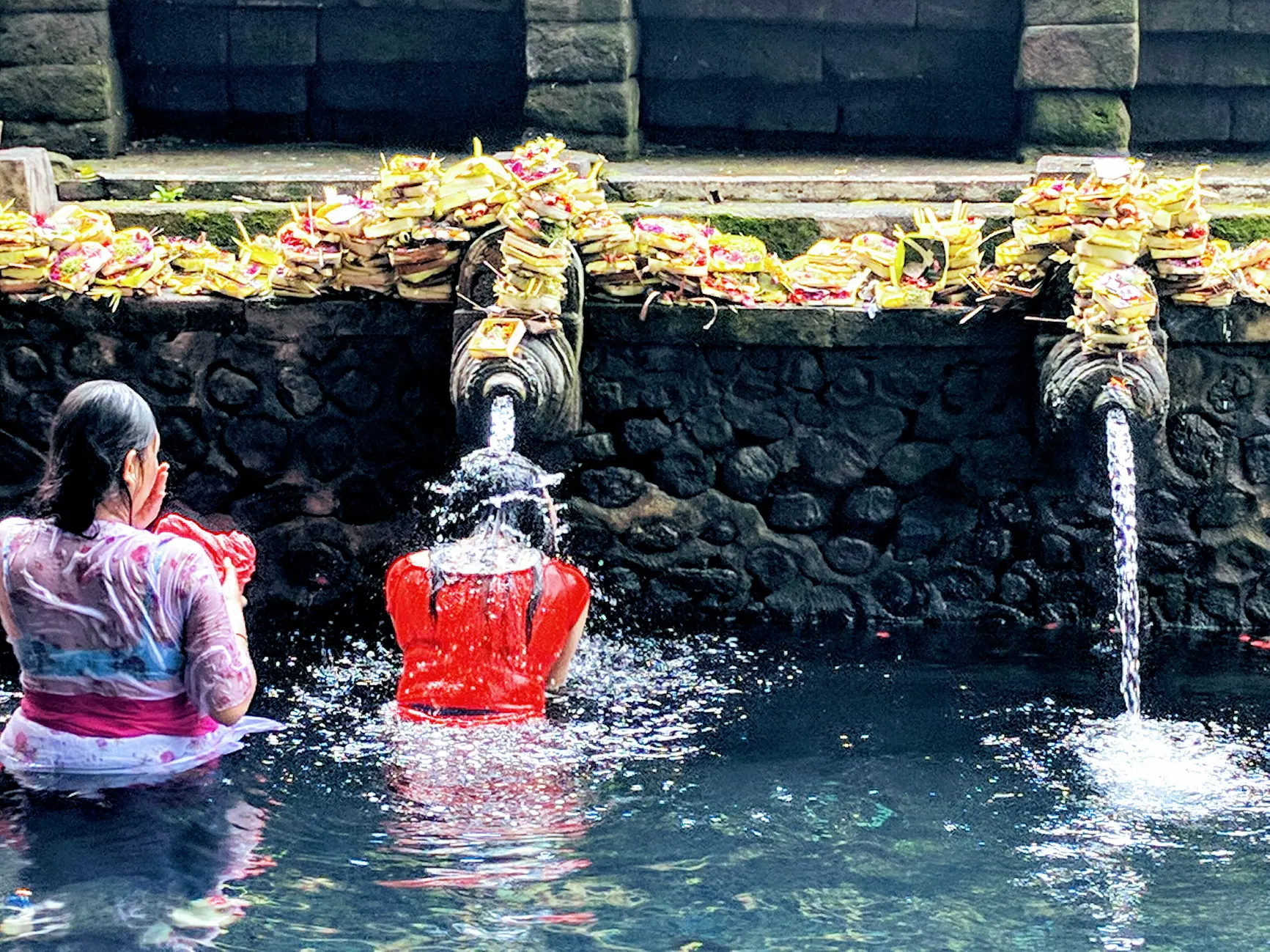 Viajeros purificándose bajo los caños de agua de Tirta Empul