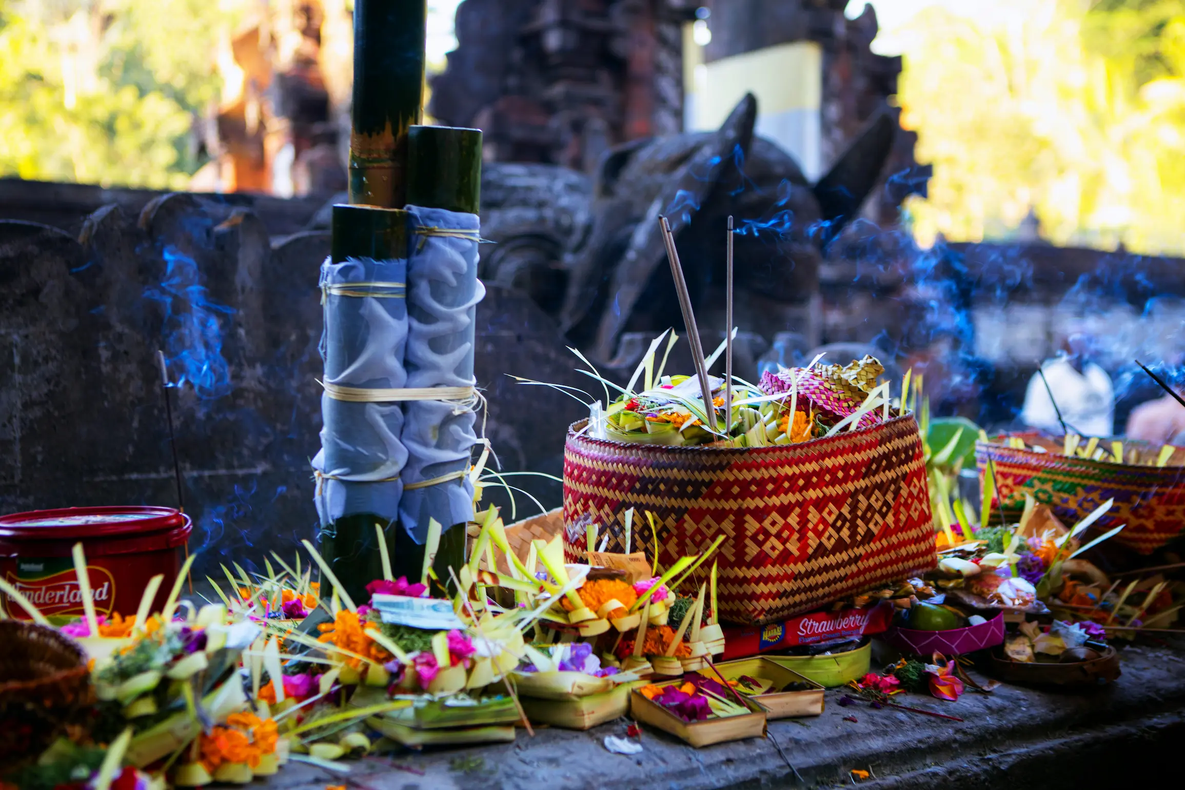 Ofrendas canang sari con flores de colores e incienso en un templo balinés