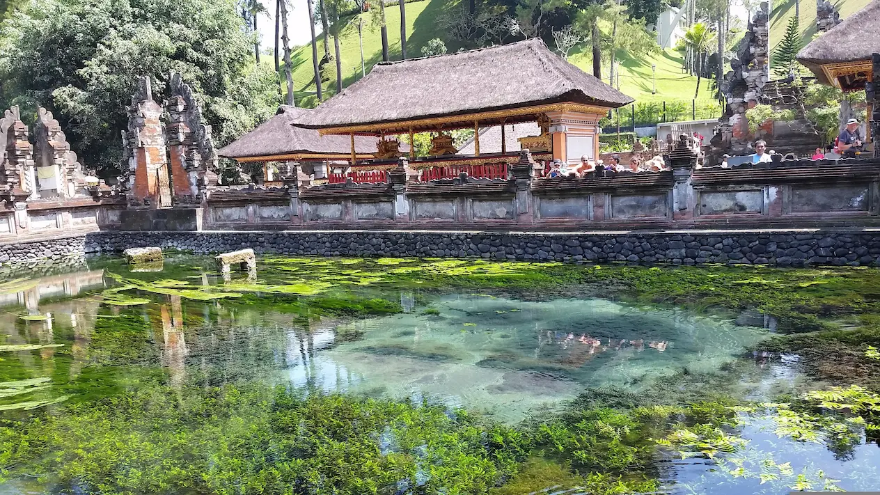 Estanque de agua cristalina con pabellones de templo al fondo en Bali