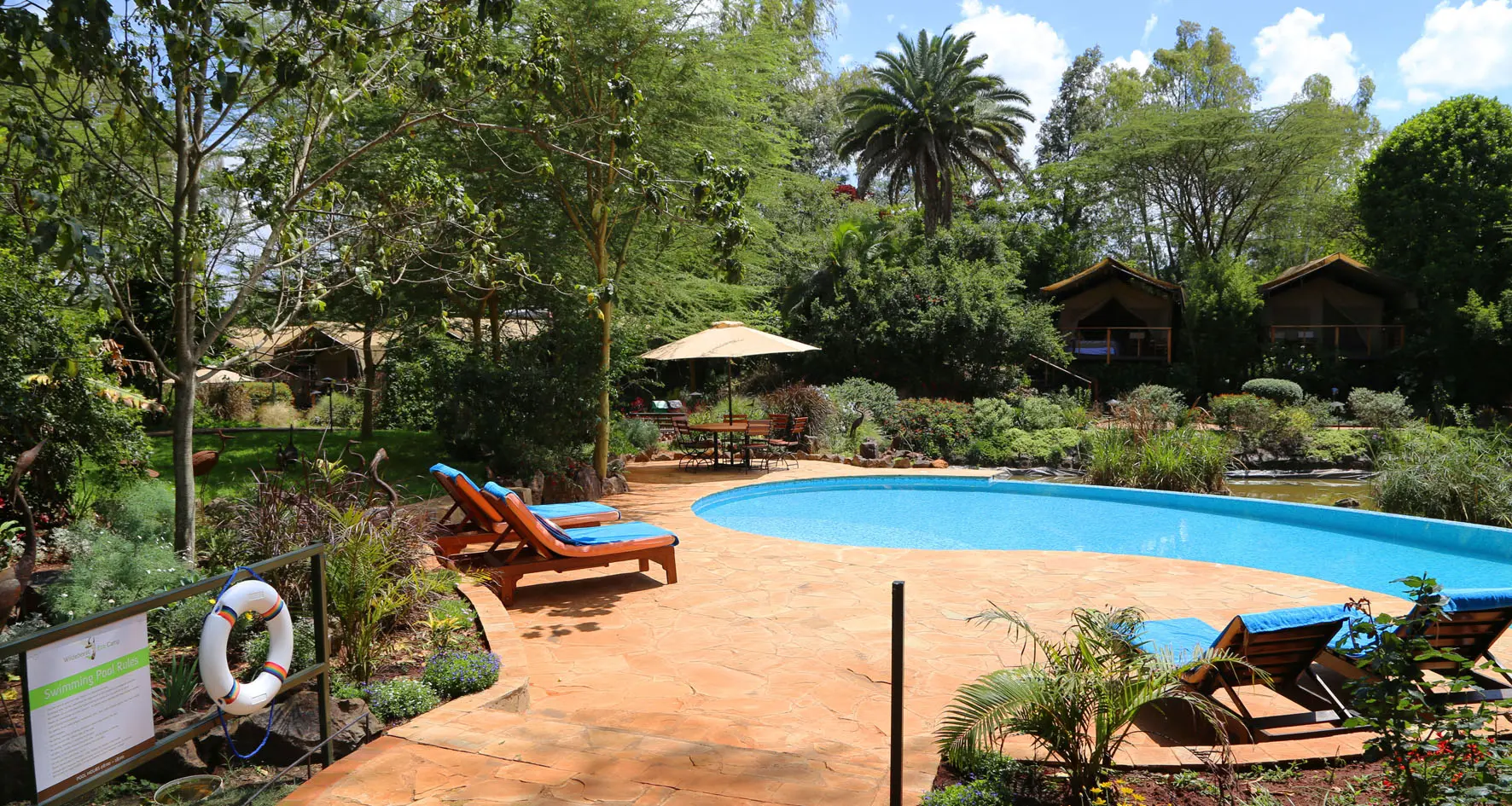 Jardín y piscina del Wildebeest Eco Camp en Nairobi, con tiendas de safari entre los árboles