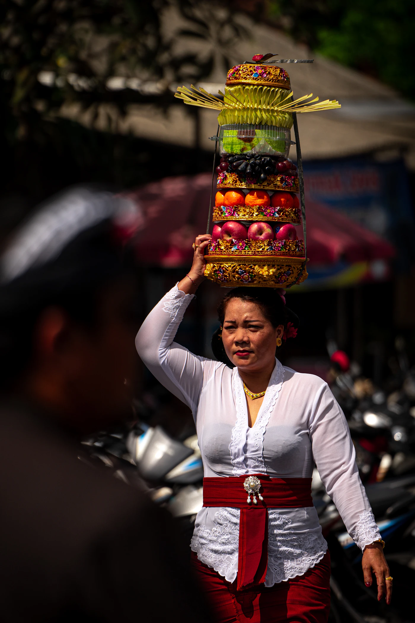 Mujer balinesa llevando sobre la cabeza una ofrenda de frutas y flores