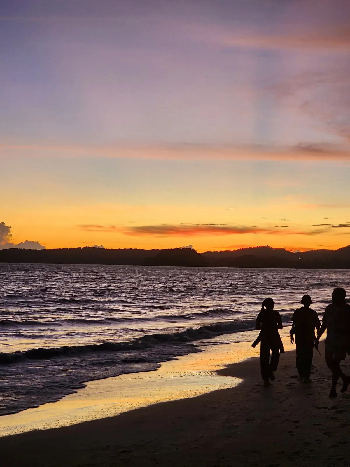 Tres viajeros caminando por la orilla al atardecer en Asia