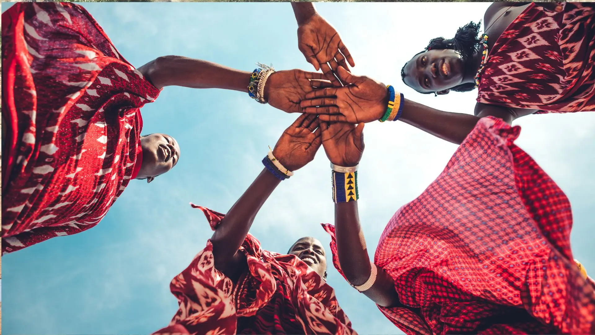 Masáis con sus shukas rojas uniendo las manos en círculo bajo el cielo de Kenia